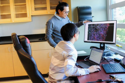 Photo of Zhe Zhu and graduate student working in the lab